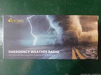 Top of box showing the DBSOARS Emergency Weather Radio with 5000mAh rechargeable battery and LED flashlight graphic and branding.