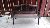 Full front view of cast metal and wood bench showing floral pattern on backrest and wooden slat seat.