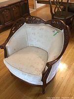 Front angled view of the chair showing the wooden frame and light floral upholstery with cushions.