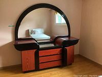 Full view of dresser with large curved mirror and glossy reddish-brown finish with black trim