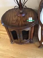 Front and full view of round wooden end table with wire mesh door, showing carved feet and decorative handles.