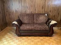 Front view of loveseat with brown patterned upholstered cushions, faux leather arms, and dark wood details. Shows overall structure and style.