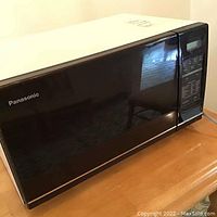 Side view of black Panasonic microwave oven showing door and top surface.
