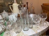 Photo of various glassware, mugs, and ceramic items on table including coffee grinder and condiment set