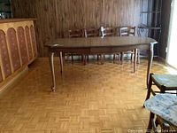 Full view of wood dining table showing the side profile, legs, and overall shape in a room setting.