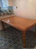 Full view of the wooden rectangular dining table showing top and legs in kitchen area
