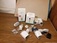Overview of all components including cameras, mounts, base station, and Arlo Chime on wood surface
