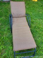 Full view of the lounge chair with cushion on grass outdoors