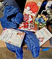 Photo shows blue snow suit, Christmas hat and socks, baby booties, two baby books.