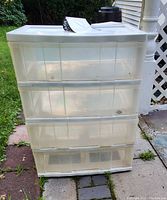 Front view of the entire plastic storage chest showing four transparent drawers and solid white top with labels on top.