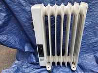 Side view of the white oil-filled radiator heater showing 7 fins and power switch on the side.