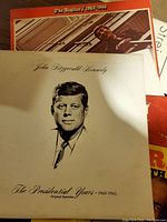 Record albums stacked showing John F. Kennedy The Presidential Years 1960-1963 and The Beatles 1962-1966 albums visible