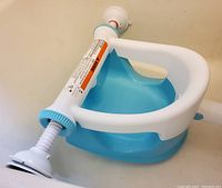 Blue and white plastic baby bath seat with suction rods for secure tub attachment.