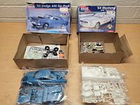 Photo showing both model car kits in original boxes with unassembled parts, tires, instructions, and decals visible.