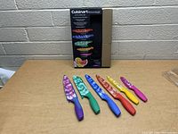 Photo of six knives of the set with colorful marbled blades and matching handles.