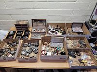 Overall view of eight cardboard trays filled with mixed jewelry pieces and boxes on tabletop