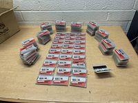 Wide view showing numerous sealed plastic cases of Toulon cutting tools arranged in rows on a table.