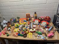 Overview of large assortment of vintage toys arranged on a table against brick wall.