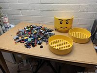 Full view of Lego head storage container parts and assorted Lego pieces on table