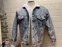 Front view of Levi's men's sherpa-lined denim jacket on a mannequin, showing button closure and sherpa collar.