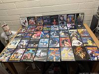 Front view of 39 anime DVDs arranged on a table, showing cover art and titles including Amon Saga, Shonen Jump, Ghost in the Shell, Spirited Away, Lupin III, Black Jack, Project A-ko, Mobile Suit Gundam and others.