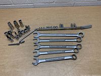 Photo showing five Craftsman combination wrenches, multiple assorted sockets, socket extensions, and a ratchet handle on a table.