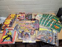 Photo showing a collection of comics and magazines including Superman issues, Wizard magazines, Sports Illustrated for Kids, Fan magazines, and Dick Tracy comic.