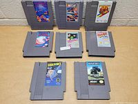 Seven Nintendo NES game cartridges arranged on a flat surface showing front labels and overall condition.