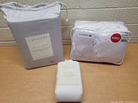 Three items: Casaluna sheet set in gray drawstring bag, Casaluna pillowcase set in cream packaging, and Lacoste pillow set in white zippered case marked King size.