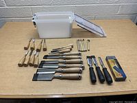 Full view of lot with all chisels, storage container, and blade box on a workbench.