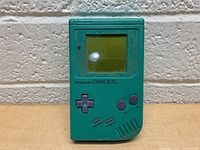 Front views of the green Nintendo Game Boy showing screen, controls and surface wear.