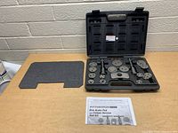 Overview photo of the tool kit with tools arranged in the open molded case, foam insert removed and owner's manual nearby on table.