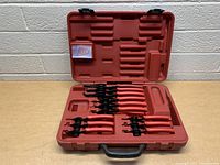Full view of red plastic carrying case open showing 8 retaining ring pliers with red handles and black jaws in molded slots inside the case.