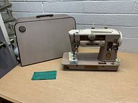 Singer Model 401A sewing machine next to original hard carrying case, small fabric swatch and spool of thread included.