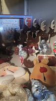 Wooden reindeer figurines with red noses and white antlers, M.J. Hummel Christmas Angels book, assorted Christmas ornaments and snowman figurines on shelf.