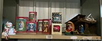 Wide shot of various boxed Hallmark ornaments with Santa candle holder and snowman stocking hanger on shelf
