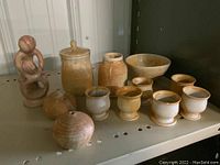 Overall view of the pottery and stone figure set on a shelf showing all items together, giving context to the lot