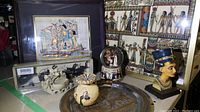 Wide view showing entire lot: framed papyrus art, queen bust, snow globe, carved vase, elephant place card holders, decorative plate, and smaller artifacts.