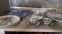 Shelf with assorted blue decorative plates, floral plates, pierced bowl, and platter.