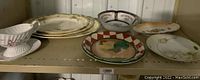 Overview photo showing multiple vintage plates, platters, bowls, and plates arranged on a shelf, highlighting the variety of patterns and styles.