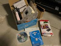 Photo of Canon Selphy CP740 printer box with printer, cables, paper, and accessories displayed inside and next to box.