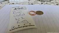 Photo showing the 10K rose gold ring alongside a Canadian quarter and a auction tag, confirming the ring is 10K gold.