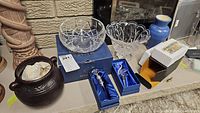 Wide view of entire lot including the crystal bowls, pottery vase, bottle stoppers, and brass ornament