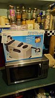 Photo of Bravetti professional deep fryer box on top of an Emerson microwave, showing packaging and fryer details
