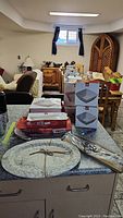Four boxes of Mayfair and Jackson dinnerware and a Jax and Marbles Lake Simcoe bamboo platter arranged on a kitchen counter and dining area