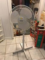 Front view of the standing fan showing the full height and cross-shaped pedestal base.