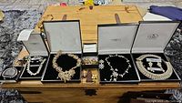 Multiple boxed sets of Indian wedding jewelry including necklaces, earrings, bracelets, brooches, hair combs displayed on wooden chest.