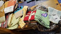 Wide view of all linens in the lot on a table, showing towels, table cloths and packaged drapes.