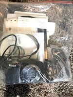 Nikon Coolpix camera and accessories in plastic bag with manuals and cables.