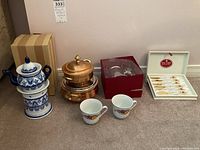 Wide view showing all items in the lot including the teapot set, tea cups, copper pots and spoon set in box.